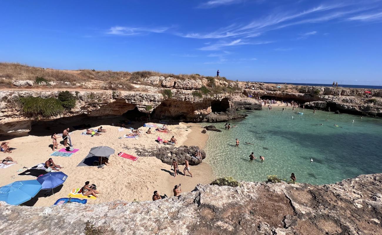 Foto af Grotta della Cala Tre Buchi med lys sand overflade