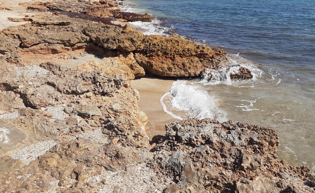 Foto af Cala l'Arjub med brunt sand og sten overflade