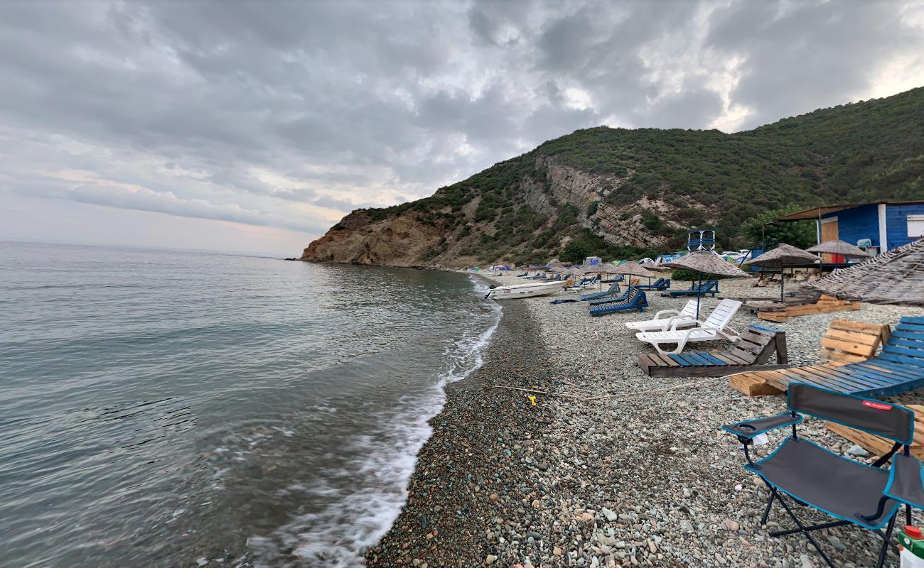 Foto af Komur Limani beach bakket op af klipperne